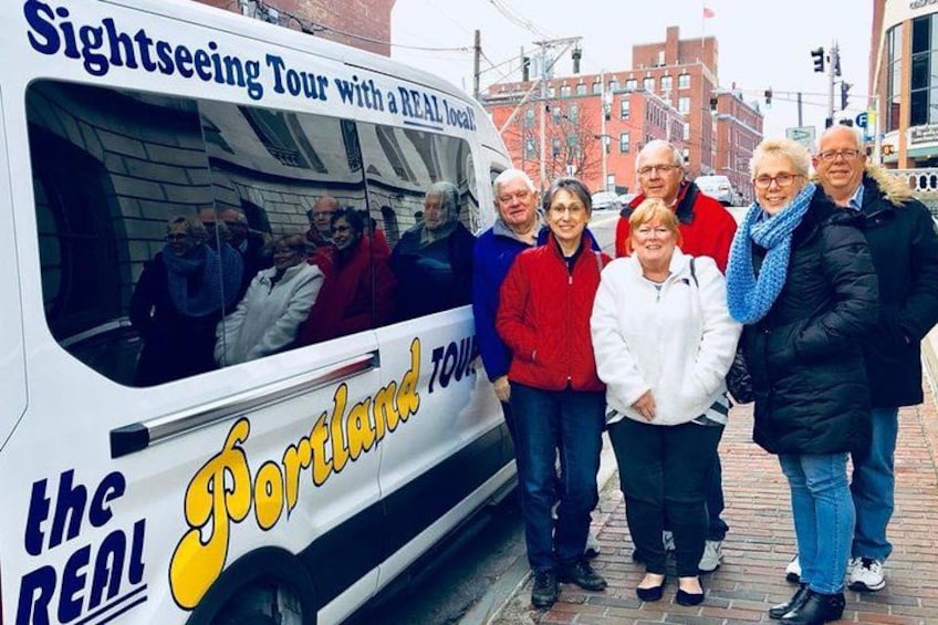 A sightseeing tour bus with passengers and a group of people standing in front of it. 4