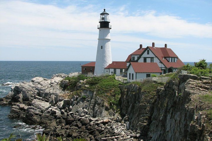 A lighthouse, a house, rocky coastline, and the ocean. 1