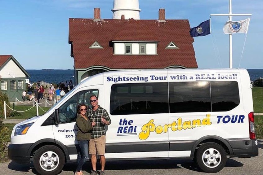 A sightseeing tour van parked in front of a historic building with a coastal view. 2