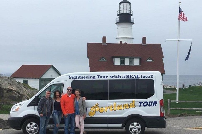 En minibuss med texten ”Sightseeing Tour with a REAL local!” och ”Portland TOUR”, ett fyrtorn och en amerikansk flagga. 2