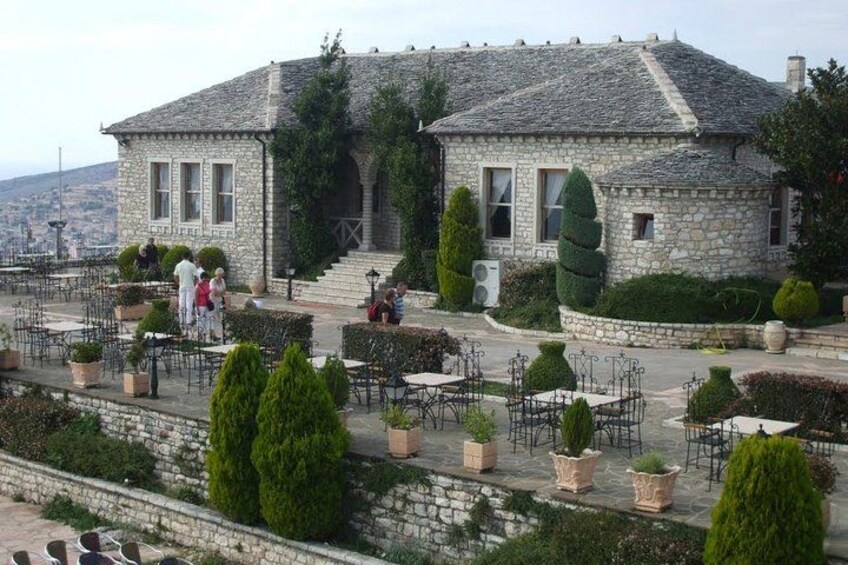 Un edificio de piedra con jardín y mesas al aire libre. 4