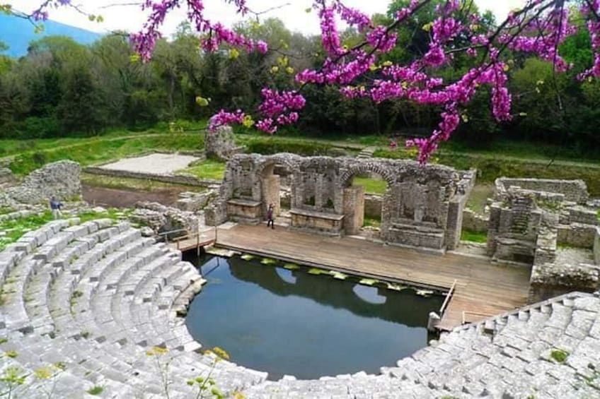 Un anfiteatro antiguo con un escenario de madera y una zona de asientos de piedra circular. 1