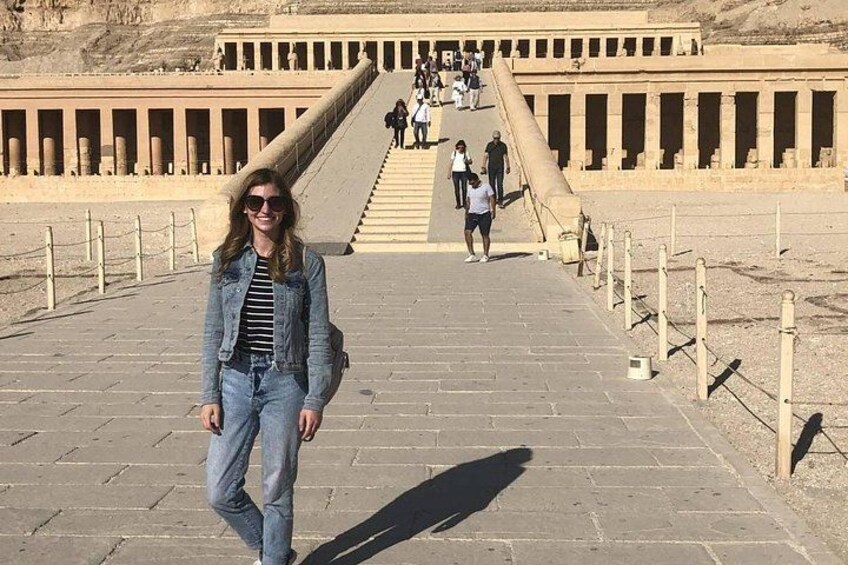 Una persona caminando por un sendero de piedra con arquitectura egipcia antigua de fondo. 3