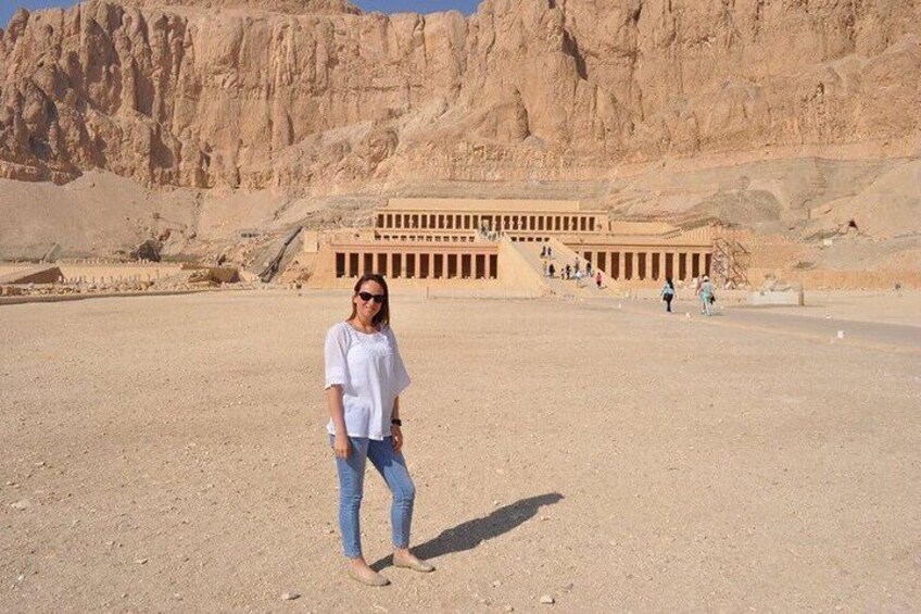 A person standing in front of a large ancient Egyptian temple with a desert landscape in the background. 2