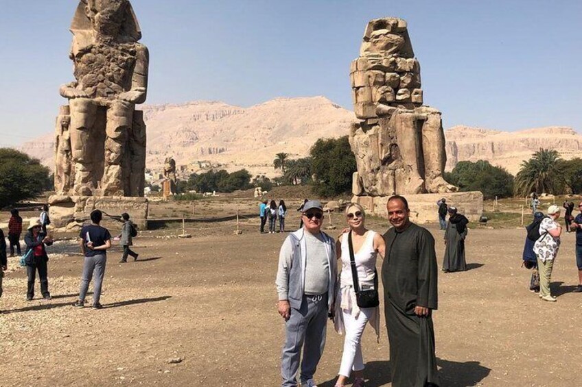Two people standing in front of ancient Egyptian statues in a desert landscape. 5