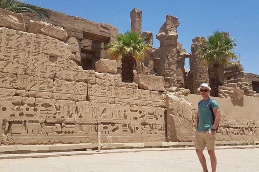 A person standing in front of ancient Egyptian ruins with hieroglyphic carvings. 3
