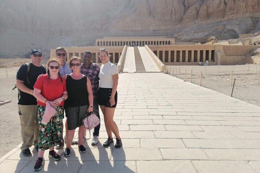 A group of people standing in front of an ancient Egyptian temple with a large staircase leading to the entrance. 4