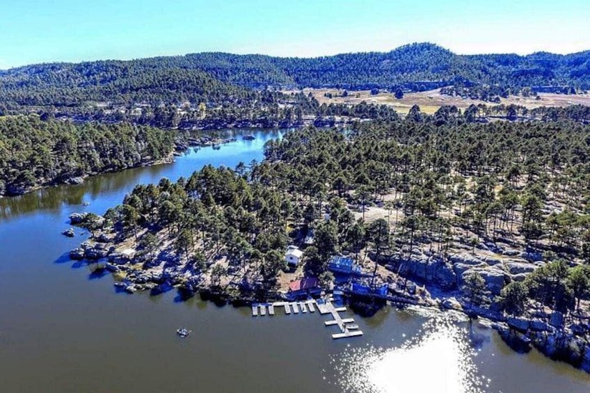 Une rivière bordée d’un quai, entourée d’une forêt dense et avec des collines en arrière-plan. 1