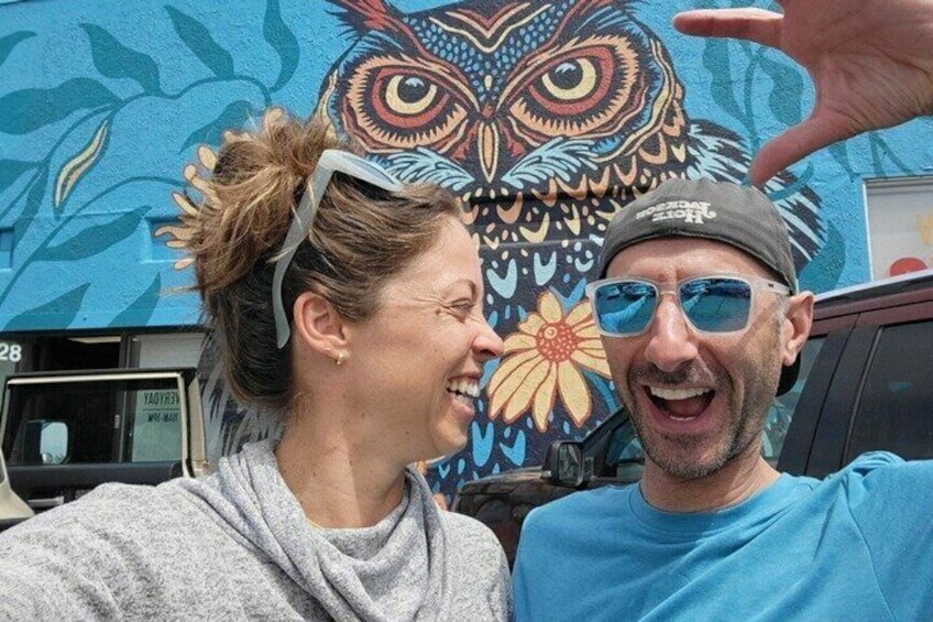 A mural of an owl with floral patterns and a vehicle in the background. 4