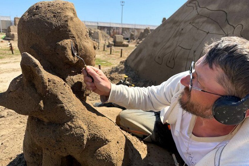 A person examining a large sand sculpture. 3