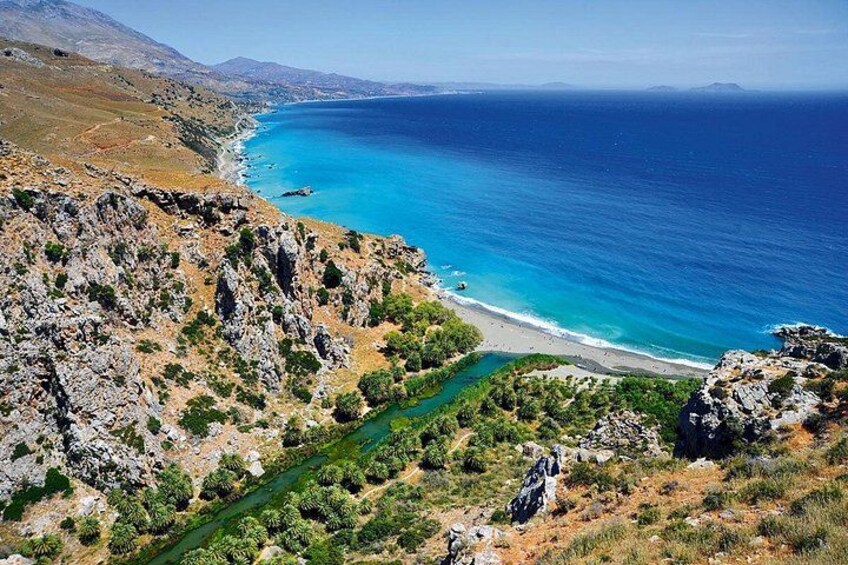 A coastal landscape with a rocky shoreline, a clear blue sea, and a narrow river flowing through the terrain. 3