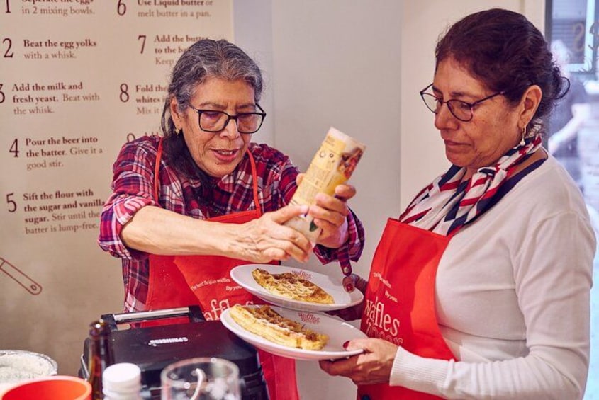 Dos personas preparando comida, una sosteniendo un batidor y la otra un tazón. 3