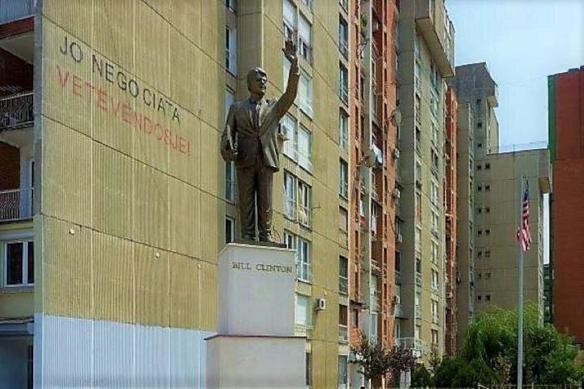 A statue of a man on a pedestal with a building in the background. 2