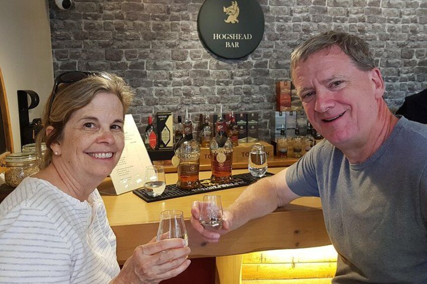 Two people toasting with drinks at a bar with a Hoghead sign. 4