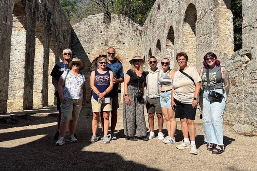 Un groupe de personnes se tient devant les vestiges d’anciens bâtiments en pierre, caractérisés par des arches. 4