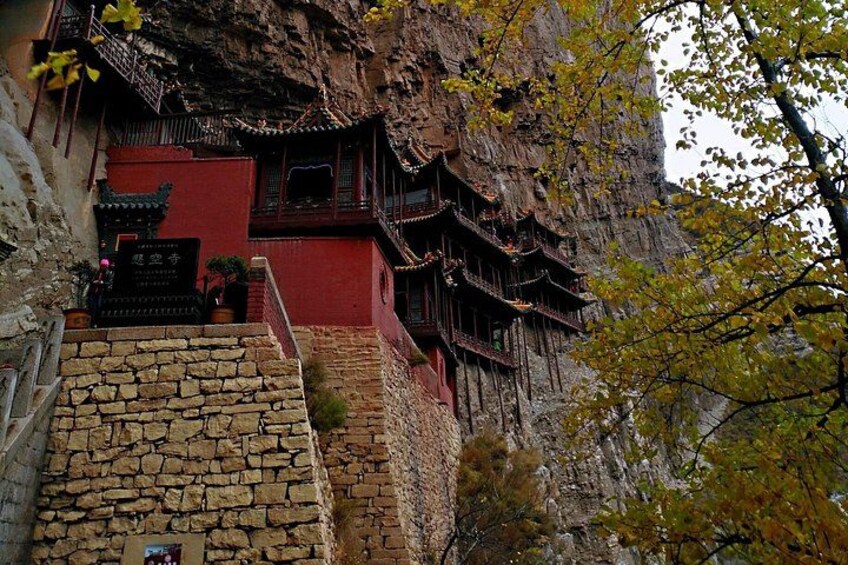 A traditional building with red walls and wooden structures built into a cliffside. 2