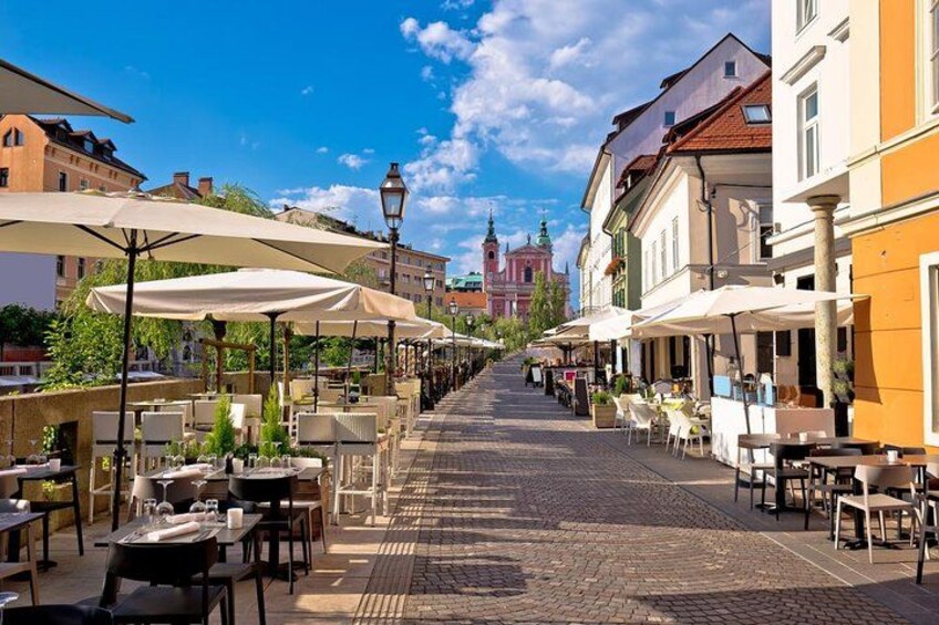 Eine Kopfsteinpflasterstraße gesäumt von Straßencafés, Tischen und Sonnenschirmen. 5