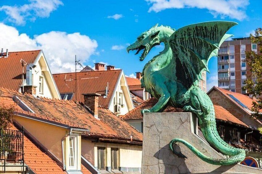 Una estatua de dragón verde sobre un pedestal en una zona residencial con tejados rojos. 4