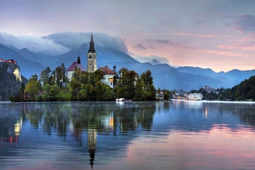 A serene lake with a church, mountains, and a clear reflection. 5