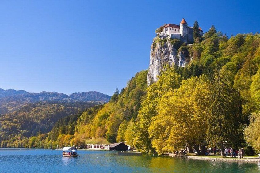A castle on a cliff by a lake with autumn trees and a boat. 4