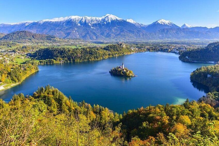 A lake surrounded by mountains, a small island with a structure, and dense forest. 1