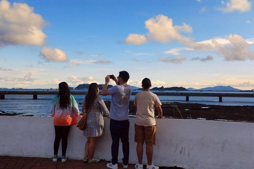A group of people standing by a waterfront, taking a photo. 2