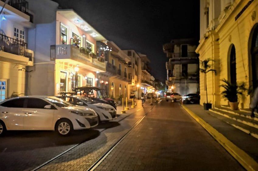 Une rue de nuit, avec des voitures garées, des immeubles dotés de balcons et des lampadaires. 5