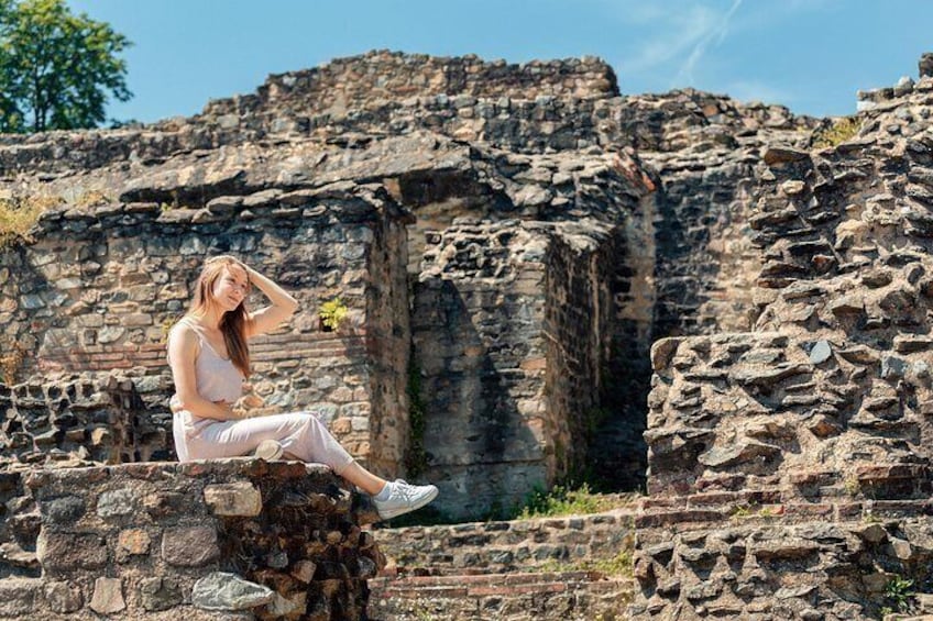 Una persona seduta su rovine di pietra con cielo sereno sullo sfondo. 2