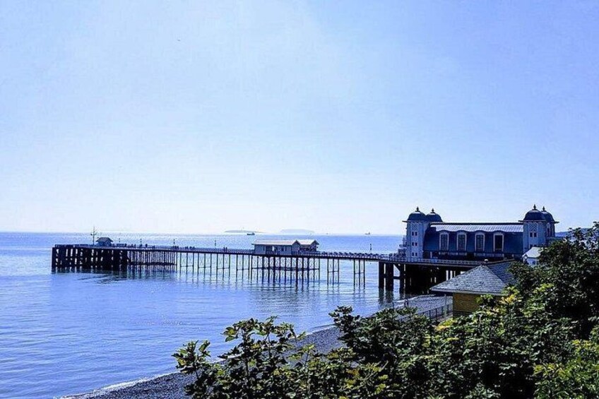 A pier extending into calm waters, a building with domed roofs, and lush greenery in the foreground. 2
