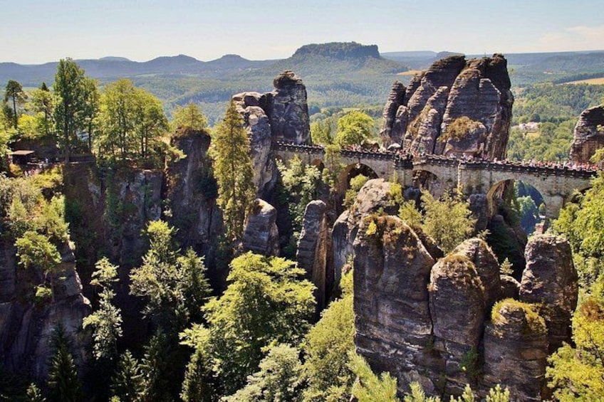 A bridge over a forested gorge with rock formations. 2
