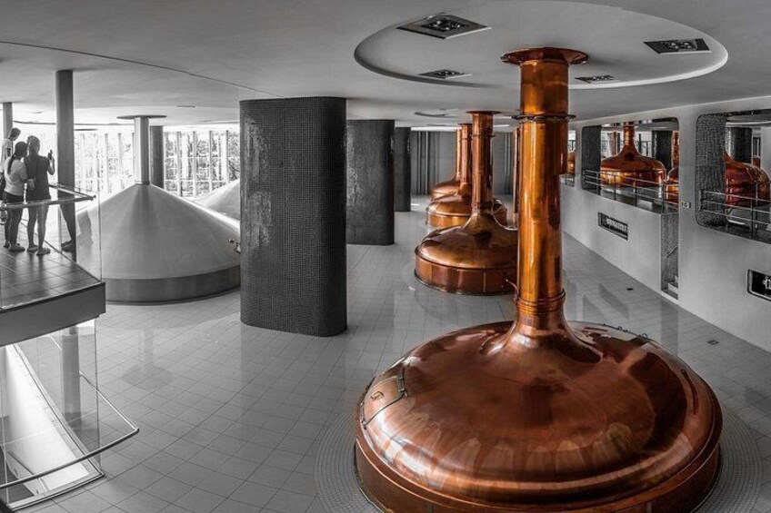 A modern interior with large copper vessels, a curved seating area, and a glass partition. 4