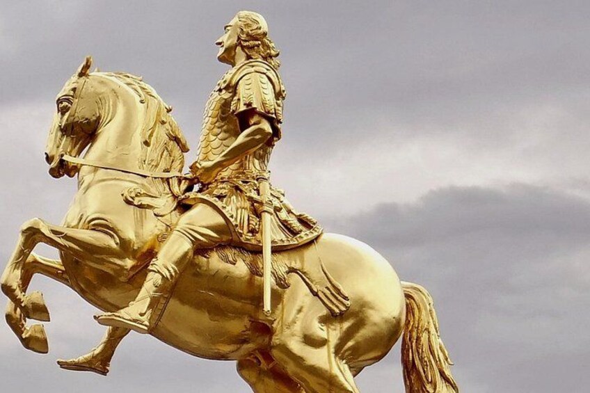 Une statue dorée représentant une figure à cheval, avec un ciel nuageux en arrière-plan. 4