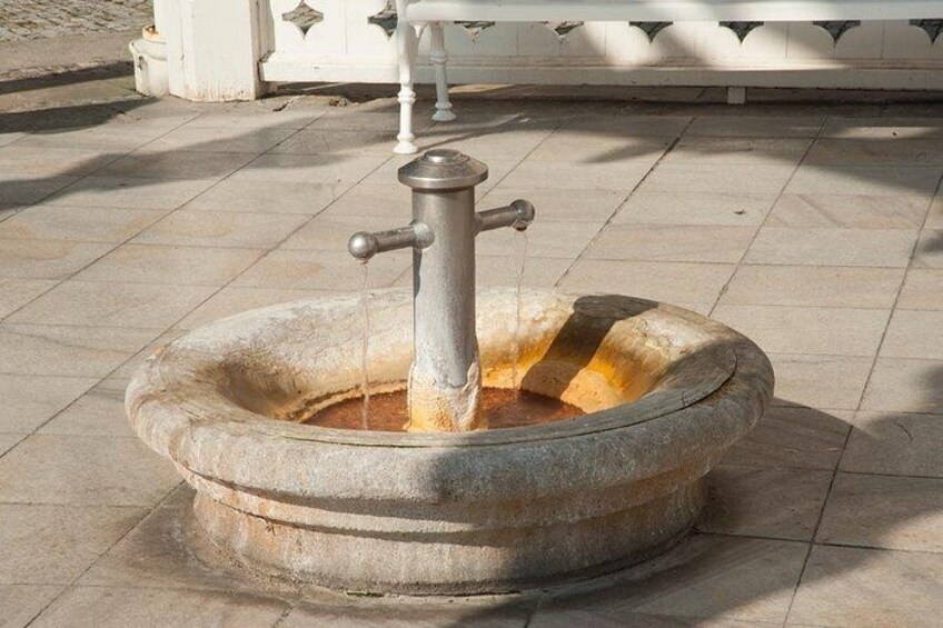 A stone fountain with a metal spout and water flowing from it. 4