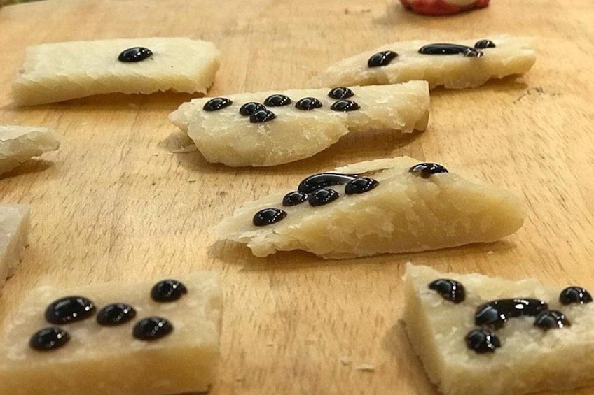 Pieces of food with black toppings on a wooden surface. 3