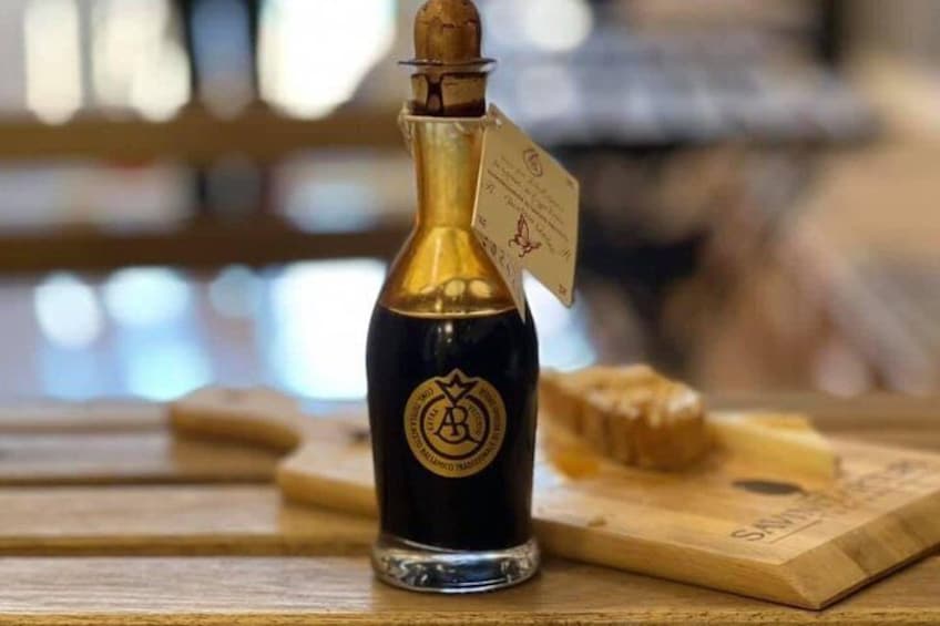 Een fles wijn met kurk, een houten snijplank met kaas, en een houten tafel. 4