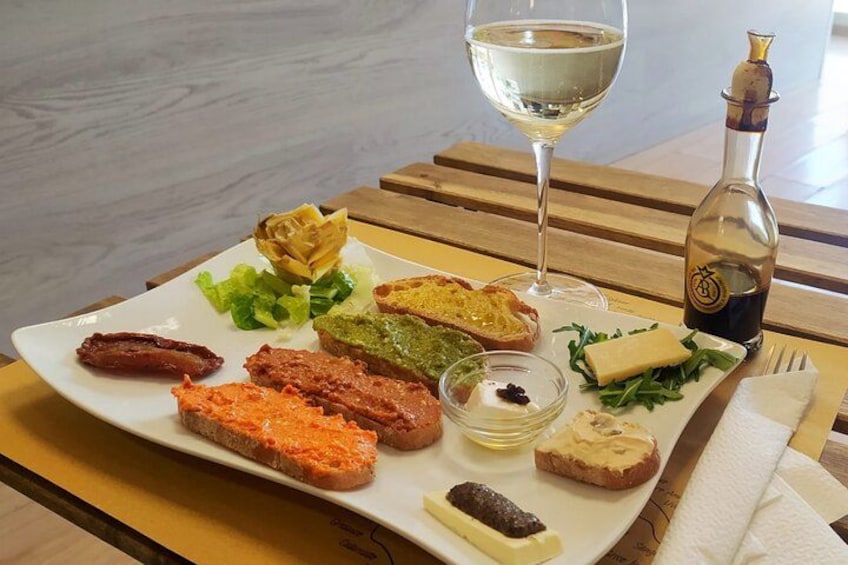 A plate of food with various items including bread, cheese, and a bottle of wine on a wooden table. 3
