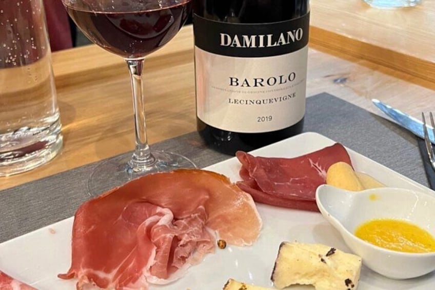 A plate of cured meats, a glass of red wine, and a bottle of Barolo wine. 4