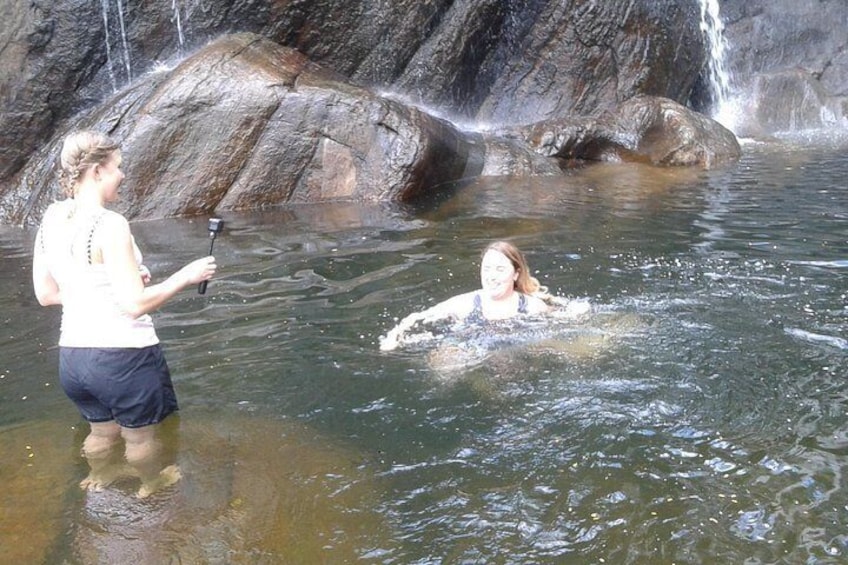 Dos personas en un entorno acuático natural, con una cascada al fondo. 3