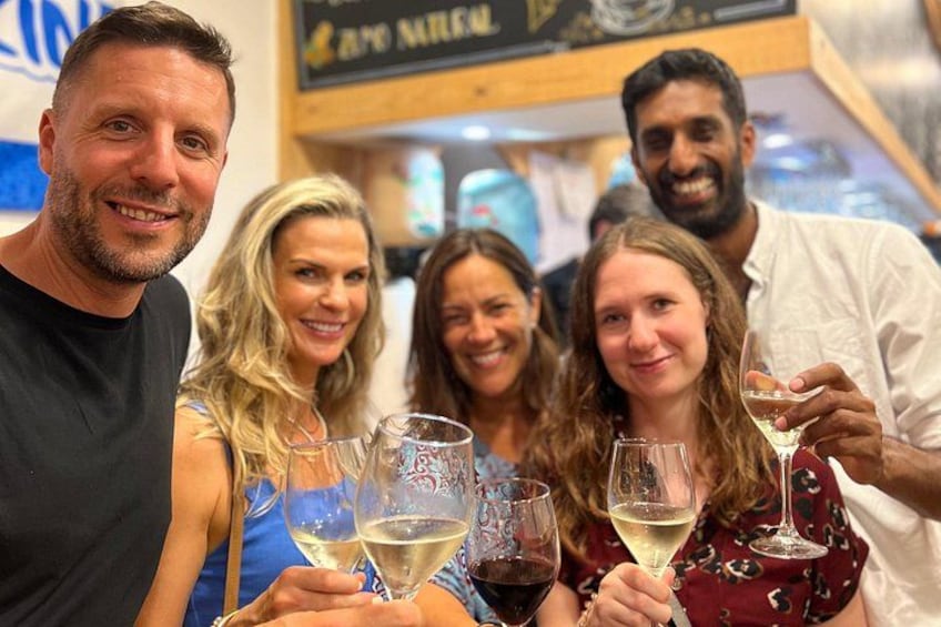 A group of people toasting with wine glasses in a bar setting. 3