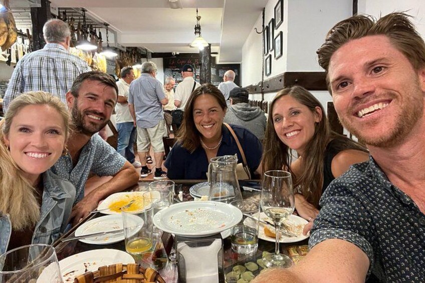 A group of people dining at a restaurant with various dishes and drinks on the table. 1