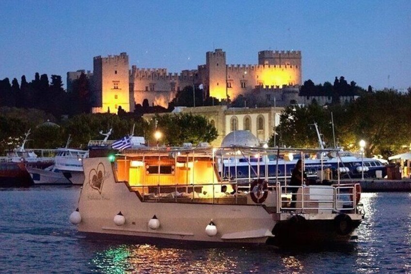 A boat with a house-like structure on the water, a castle in the background, and boats docked nearby. 4