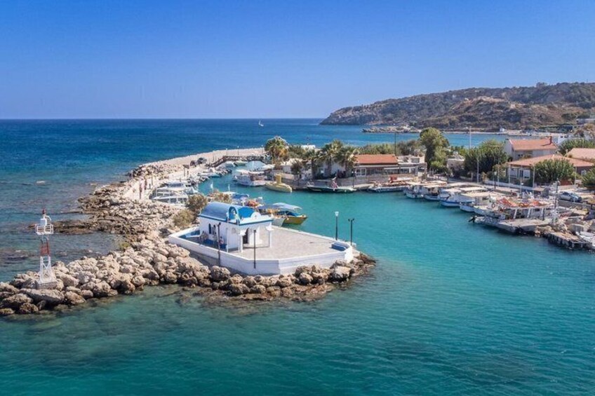 A coastal marina with boats, a lighthouse, and a small island with a white building. 2