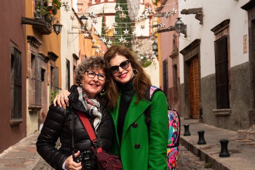 Dos personas de pie en una calle estrecha flanqueada por edificios. 3