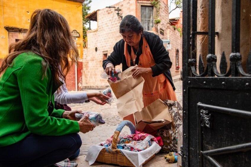 Dos personas intercambiando objetos, con una cesta y bolsas en el suelo. 2