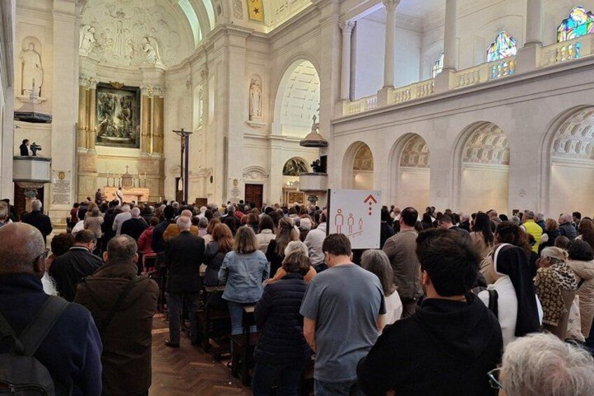 Eine große Menschenmenge in einer Kirche mit hohen Decken und Bogenfenstern. 5