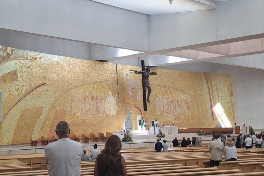 Innenansicht einer Kirche mit einer großen Darstellung der Kreuzigung, Kirchenbänken und Besuchern. 4
