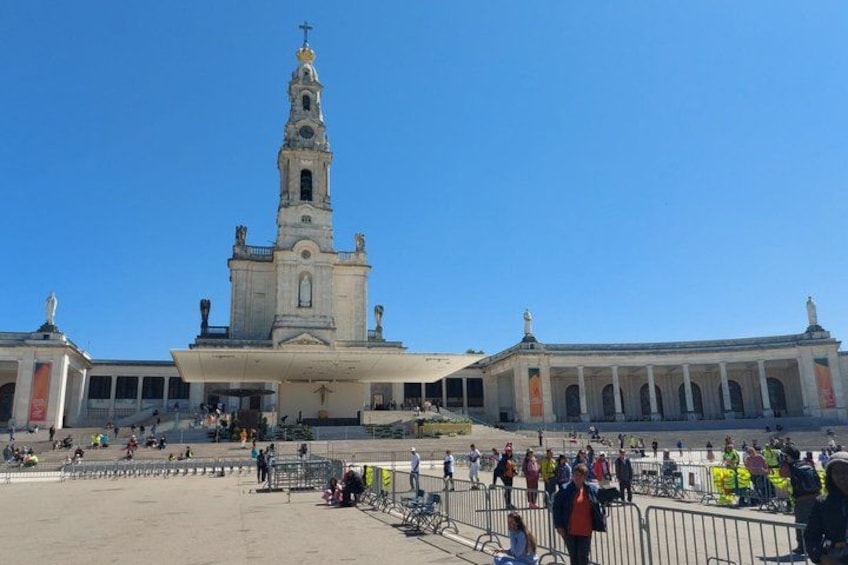 Ein großes historisches Gebäude mit einem markanten Turm, einem breiten Platz und einer Menschenmenge. 3