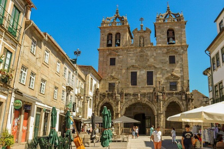 A historic building with a bell tower, surrounded by cafes and outdoor seating. 4