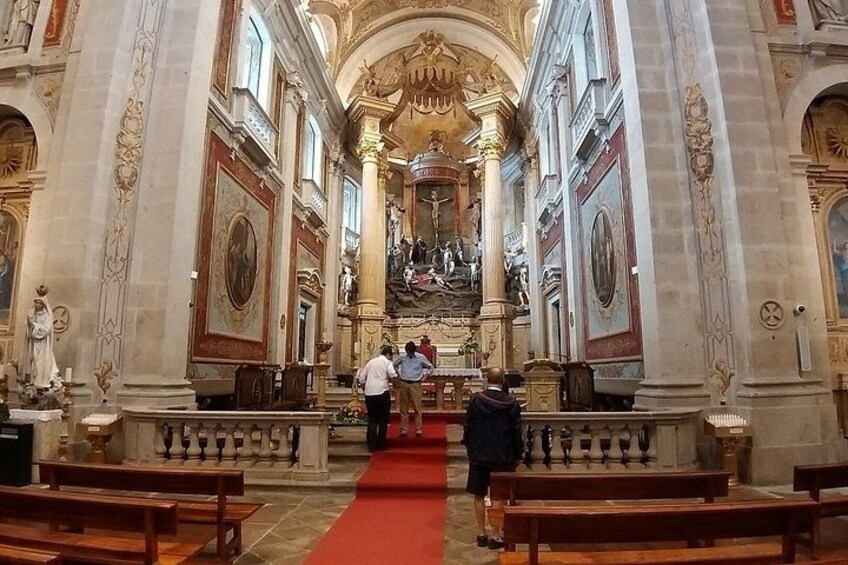 An ornate church interior with high ceilings, detailed frescoes, and a central altar. 5
