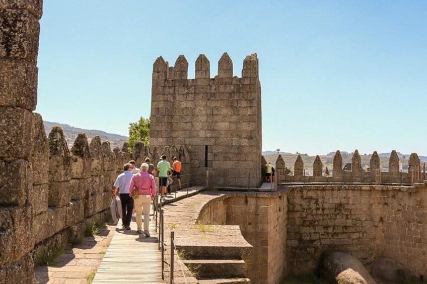 A stone wall with a gate, a clear sky, and a hilly landscape in the background. 1